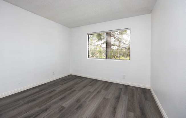 an empty room with wood floors and a window