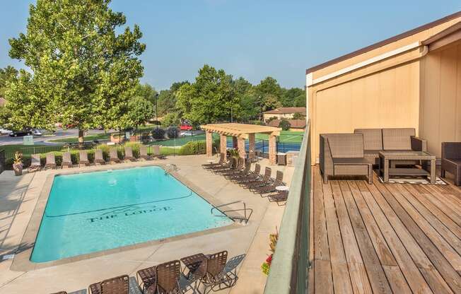 a swimming pool with chairs and a poolside deck with a fence at Lodge of Overland Park Apartments, Overland Park