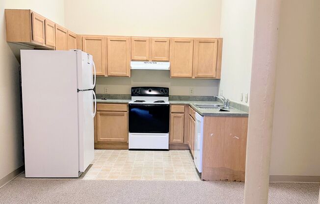 an empty kitchen with wooden cabinets and a refrigerator and stove