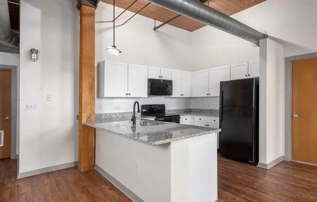 a kitchen with an island and a black refrigerator