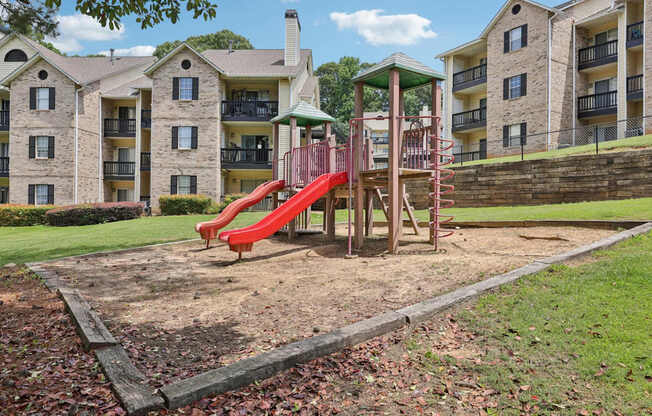 A red playground with apartment buildings in the background at Gwinnett Square Apartments in Duluth, GA
