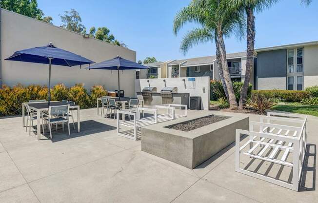 A patio with a table, chairs, and umbrellas.