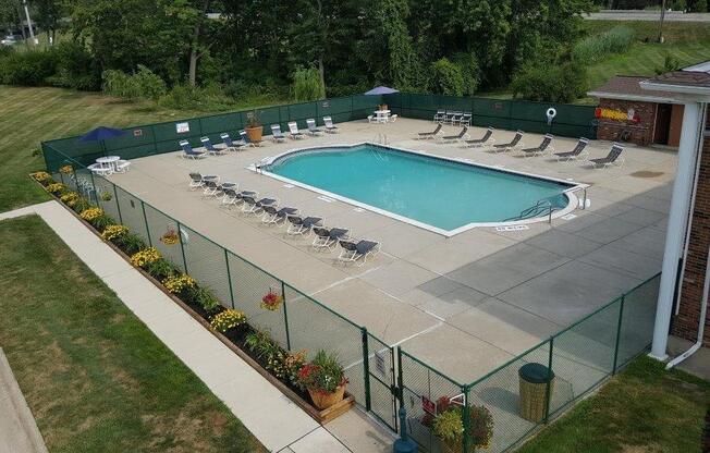 a pool with lounge chairs and umbrellas in front of a building