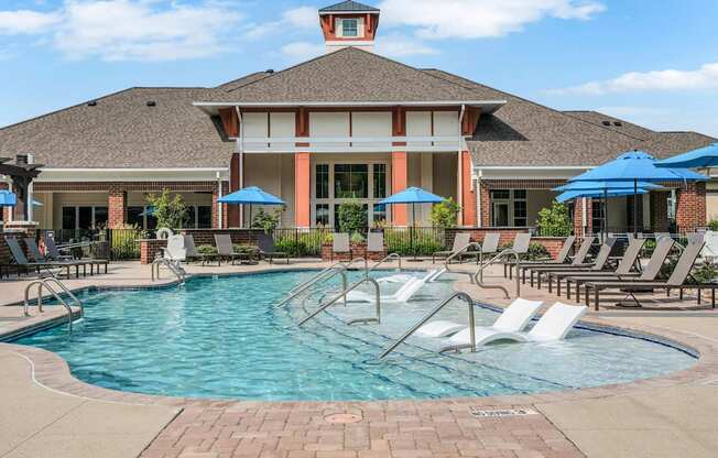 A pool with a slide and chairs around it.