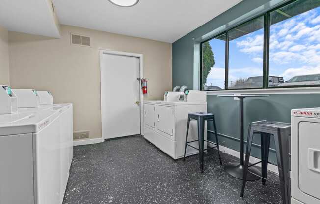 a laundry room with washing machines and a counter with two stools  at Park On Canal Apartments, Clinton Twp, MI