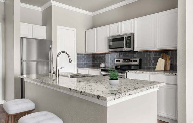 A kitchen with a marble countertop and white cabinets.