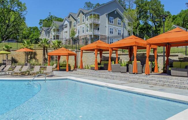 a swimming pool with orange umbrellas in front of an apartment building