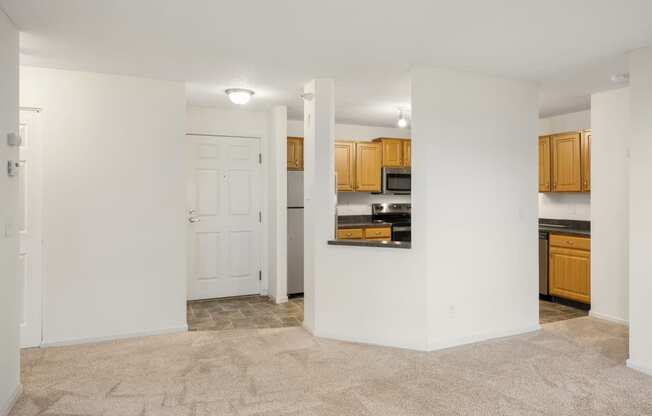 the living room and kitchen of an empty apartment with white walls and wood cabinets