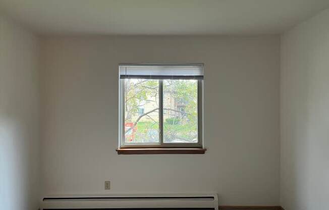 A room with a window and a white wall.