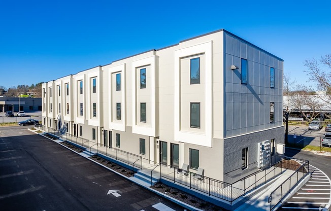 A modern building with a grey and white exterior and a parking lot in front.