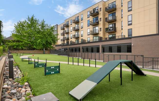 a park with grass and benches in front of an apartment building