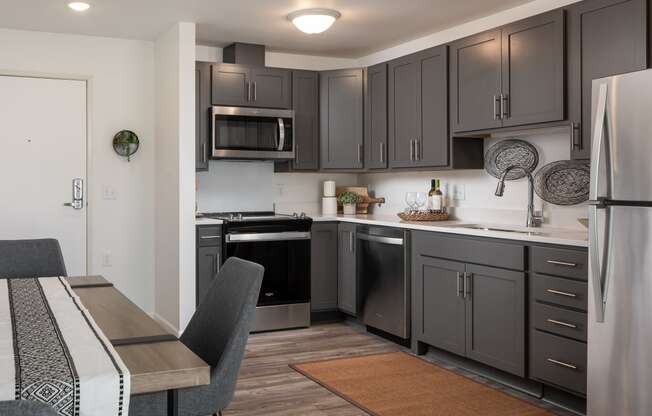 a kitchen with black cabinets and stainless steel appliances and a dining room table