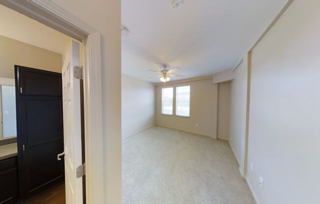 an empty living room with a ceiling fan and a window