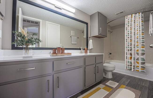 A bathroom with a sink, mirror, toilet, and shower.