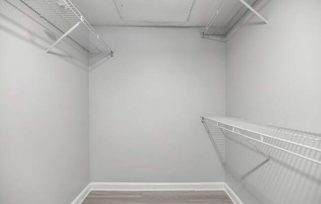 room with white walls and a white closet with white shelves and racks on the wall