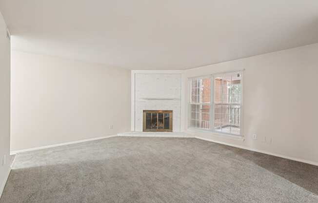 A large empty room with a fireplace and a window.