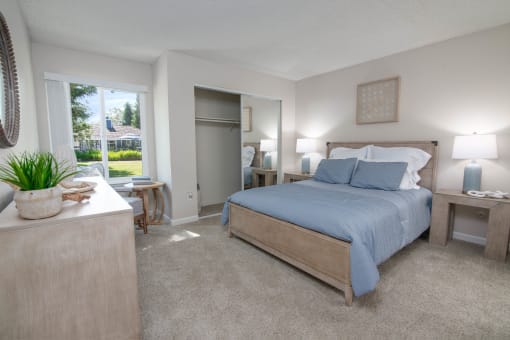 Model apartment master bedroom with a bed and a dresser and a window