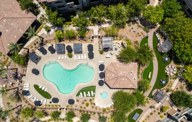 an aerial view of a swimming pool with umbrellas and trees