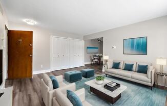 A living room with a white couch and a blue ottoman.