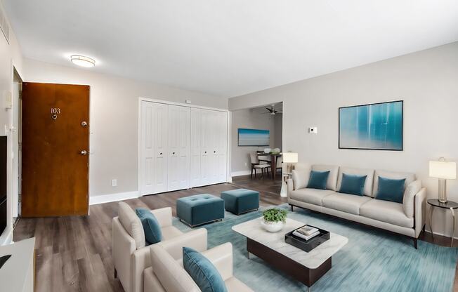 A living room with a white couch and a blue ottoman.