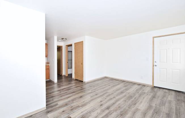 an empty living room with white walls and wood floors