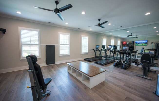 a gym with cardio machines and weights on a wooden floor