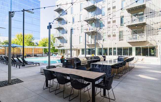 A modern outdoor dining area with tables and chairs is set up in front of a contemporary building.