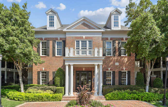 A large, red brick house with a white porch and black shutters.