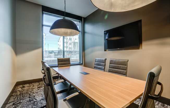 a meeting room with a large window and a wooden table and chairs