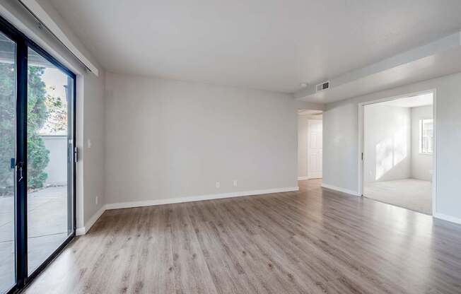 A spacious room with wooden flooring and white walls.