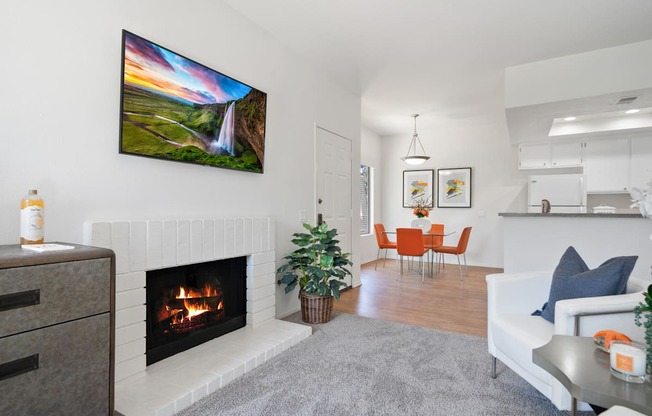 a living room with a fireplace and a dining room in the background