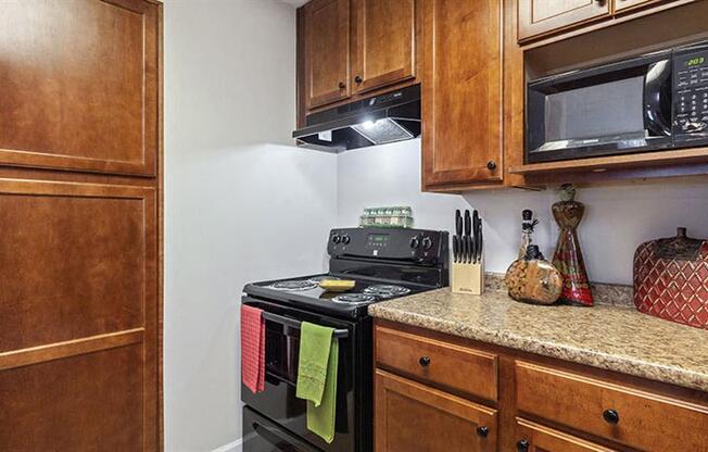 a kitchen with a stove and a microwave at Bedford Parke Apartments, Warner Robins