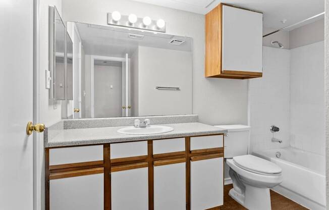 A white bathroom with a toilet, sink, and mirror.