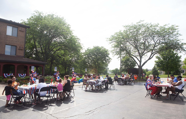 a large group of people sitting at tables in a parking lot