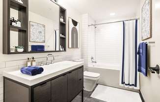a bathroom with white tile walls and a white sink with a blue towel on it