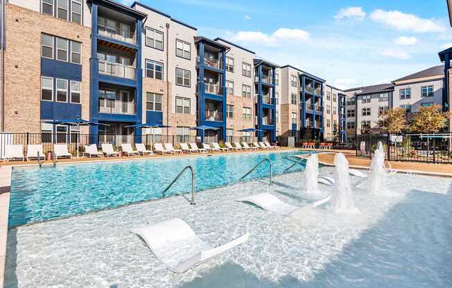 A pool with a fountain and lounge chairs at Preston Ridge Cary, NC.