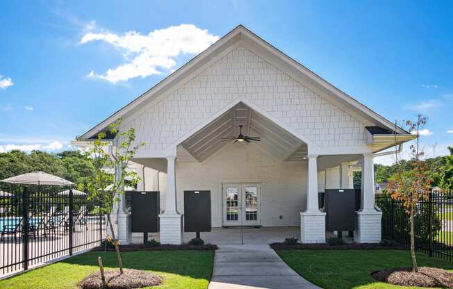 the front of a white church with a black fence and grass