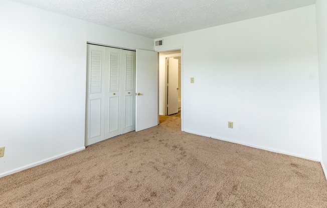 an empty living room with carpet and a door to a hallway
