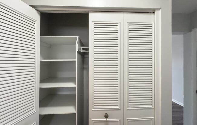 a walk in closet with white closet doors and shelving