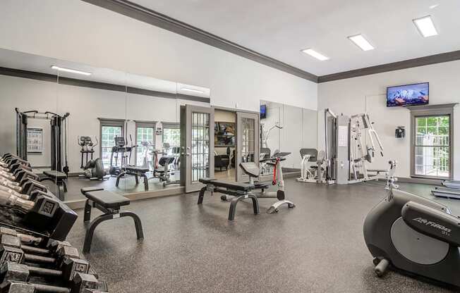 a gym with weights and cardio equipment in a large room with windows