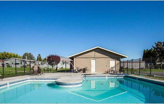 Swimming pool and pool house with lounge chairs and trees in the distance at Park View Apartments, Wenatchee Washington