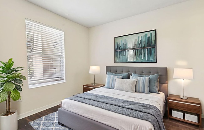 A bedroom with a large bed and a potted plant.