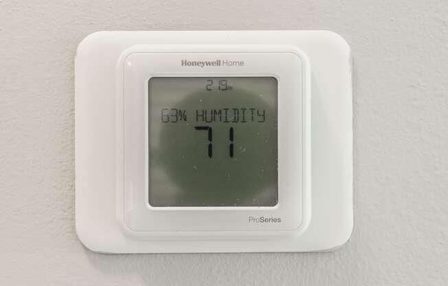 a white thermostat on a wall with an 11 on it