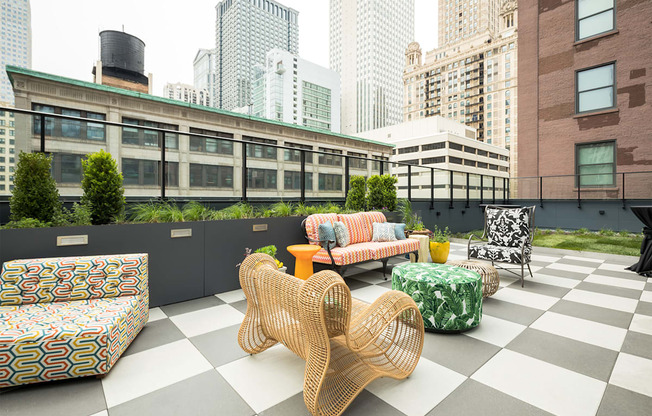 a rooftop lounge area with chairs and tables and skyscrapers
