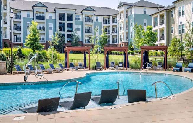 an outdoor pool with chairs and an apartment building in the background