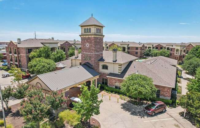A large building with a tower is surrounded by other buildings and trees.