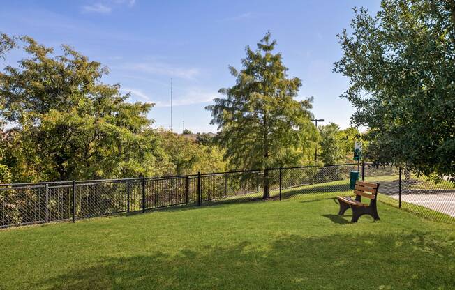 Private fenced-in off-leash dog park with bench at Avenues at Craig Ranch apartments for rent