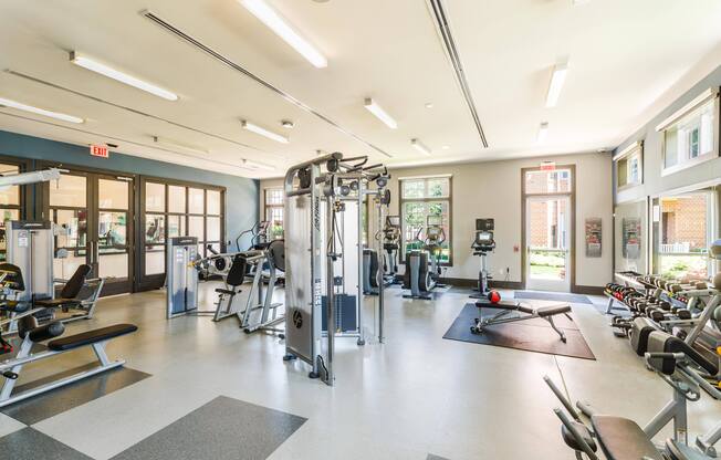 A gym with a variety of equipment including treadmills, weights, and exercise machines.