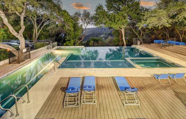 the swimming pool at the resort has a wood deck with blue chairs