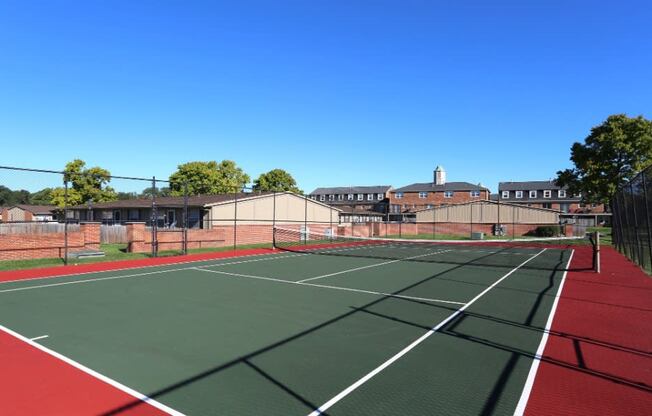 Tennis court with buildings in the background.